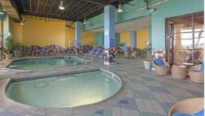 A large indoor swimming pool with a tiled floor, surrounded by lounge chairs and a seating area with tables. - Bch Q 1BR 1BA w Ocean Front Balcony - sleeps 6 (Virginia Beach)
