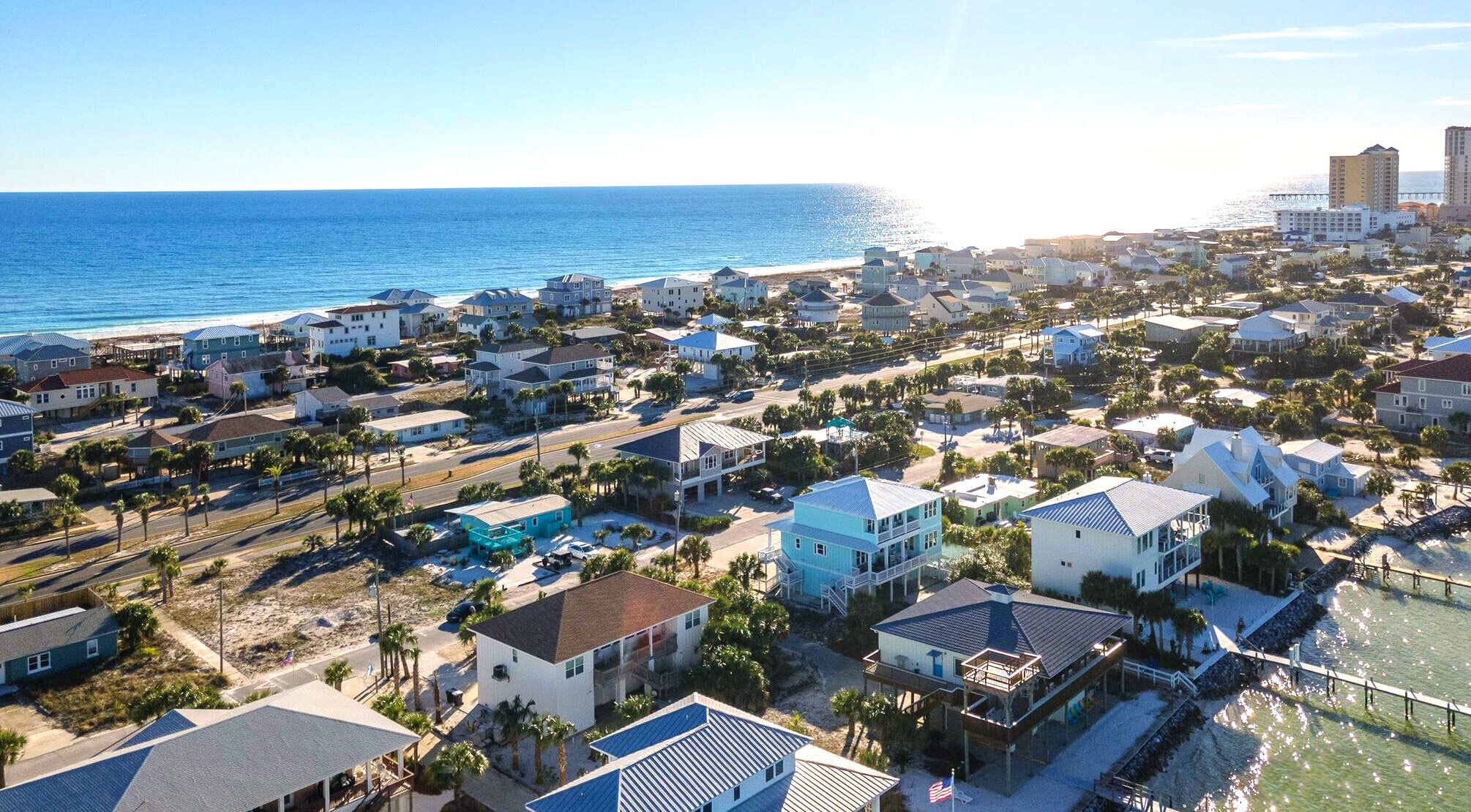 A coastal residential area with houses, a beach, and a pier.
