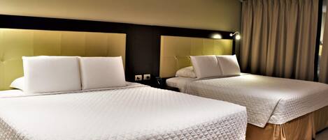 A hotel room with two beds, each with white bedding and headboards.