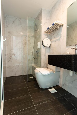 Een moderne badkamer met een douche met glazen wand, een toilet en een zwart aanrechtmeubel met een spiegel.