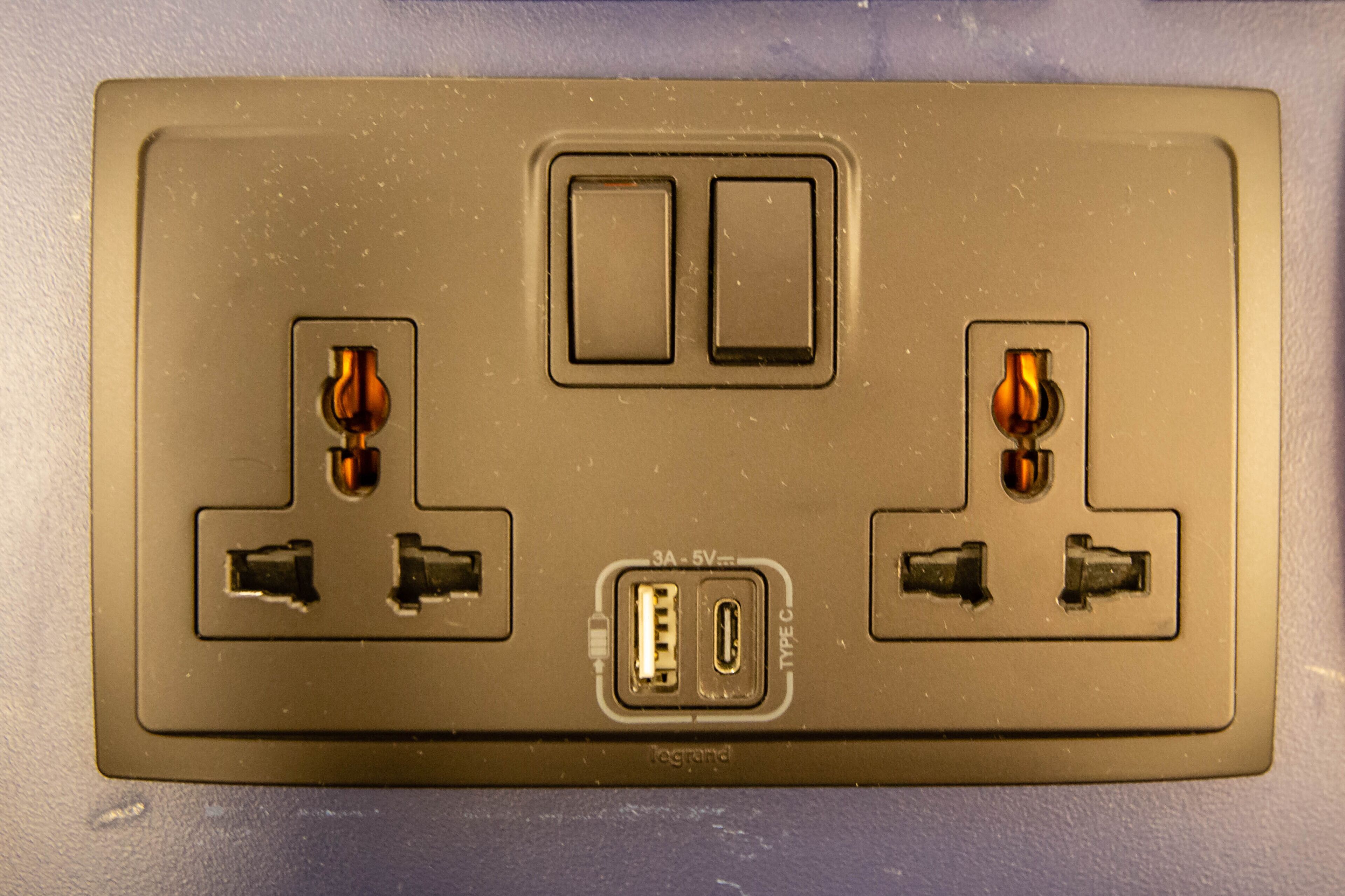 A wall-mounted electrical outlet with two switches and two USB ports.