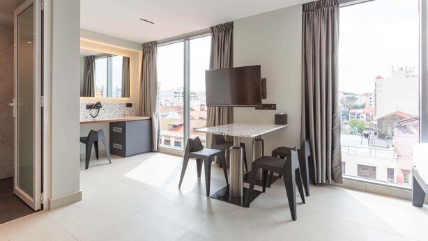 Ein modernes Hotelzimmer mit Essbereich, großen Fenstern und Blick auf die Stadt.