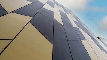 Un edificio moderno con fachada geométrica y cielo despejado al fondo.