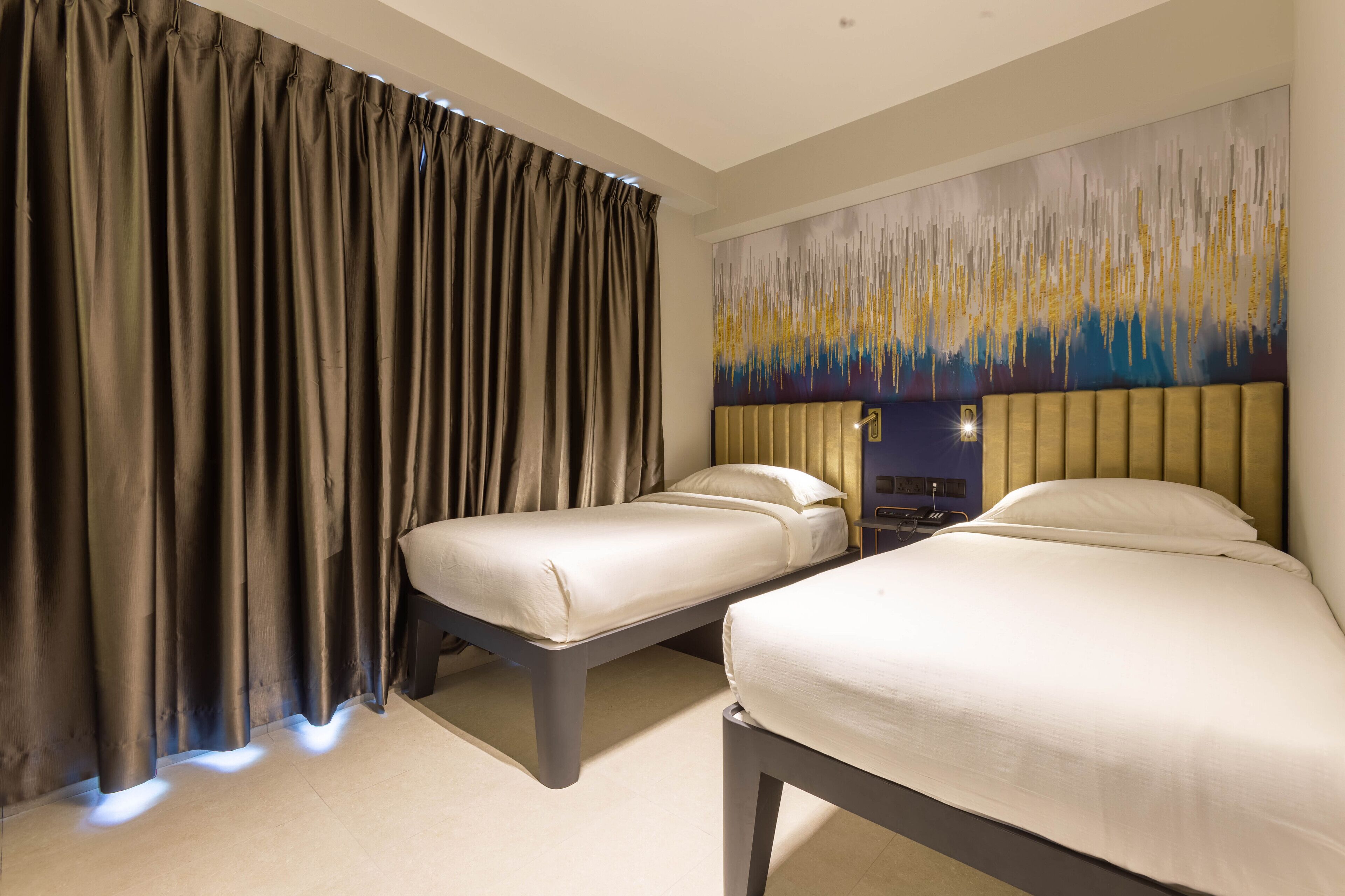 Habitación de hotel con dos camas, un cuadro abstracto grande en la pared y una ventana con cortinas.
