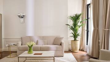 A living room with a sofa, coffee table, and a large potted plant.