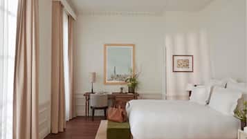 A hotel room with a bed, a desk, a chair, a lamp, and a framed picture on the wall.