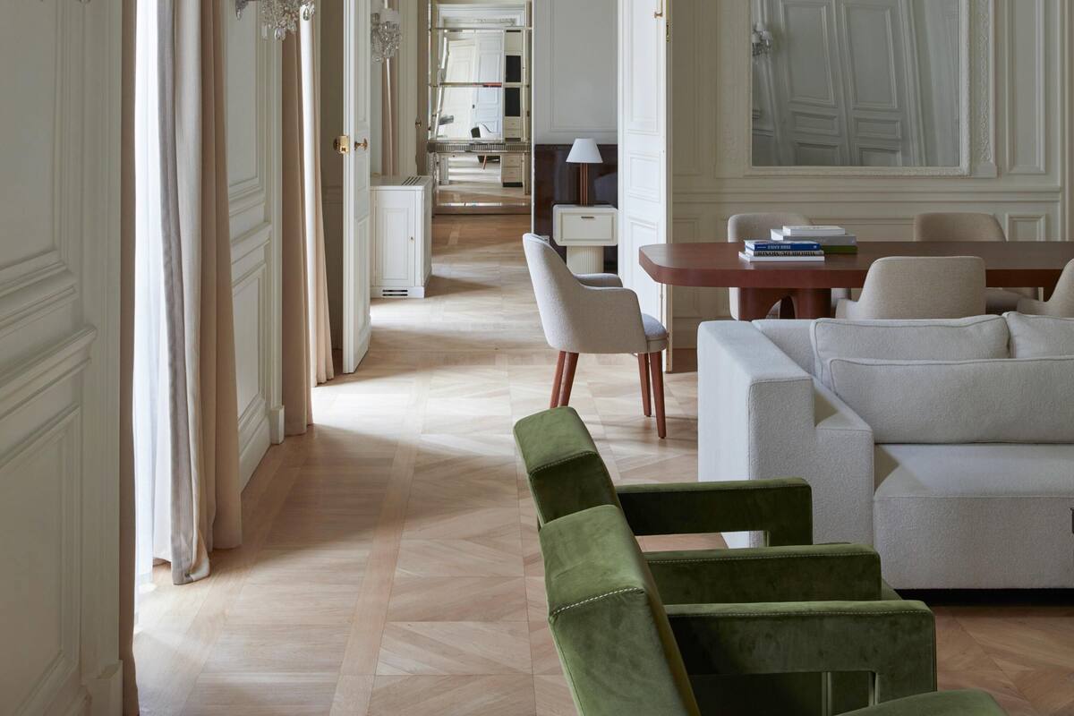 A spacious room with a large sofa, a dining table, and a mirror.