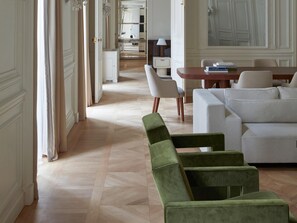 A spacious room with a large sofa, a dining table, and a mirror.