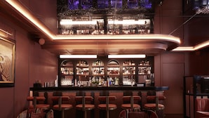A bar area with multiple stools and a bar counter, featuring a variety of bottles and glasses. - Maison Delano Paris (Paris)
