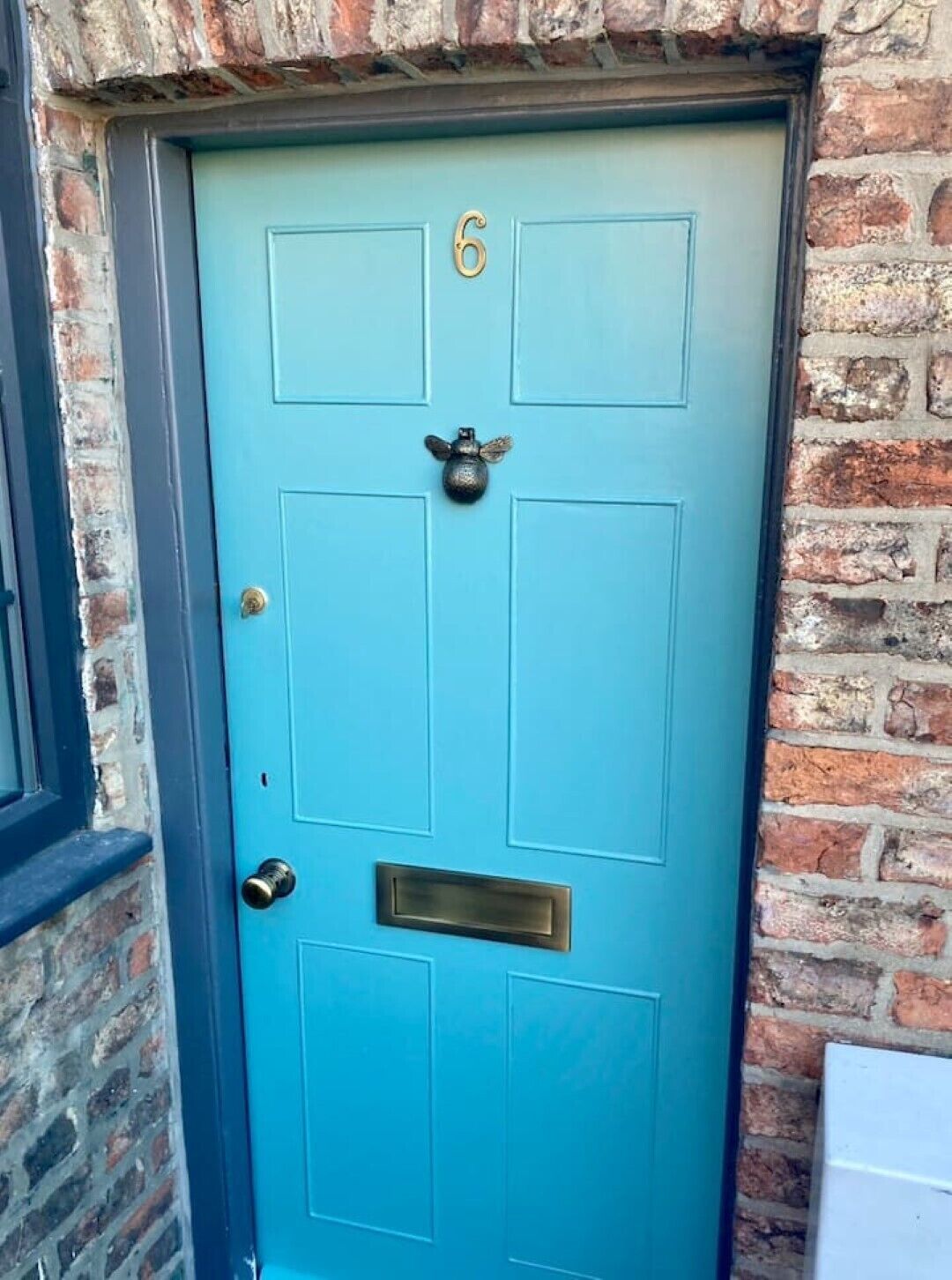 A blue door with the number 6, a brass knocker, and a mail slot.
