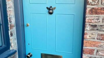 A blue door with the number 6, a brass knocker, and a mail slot.