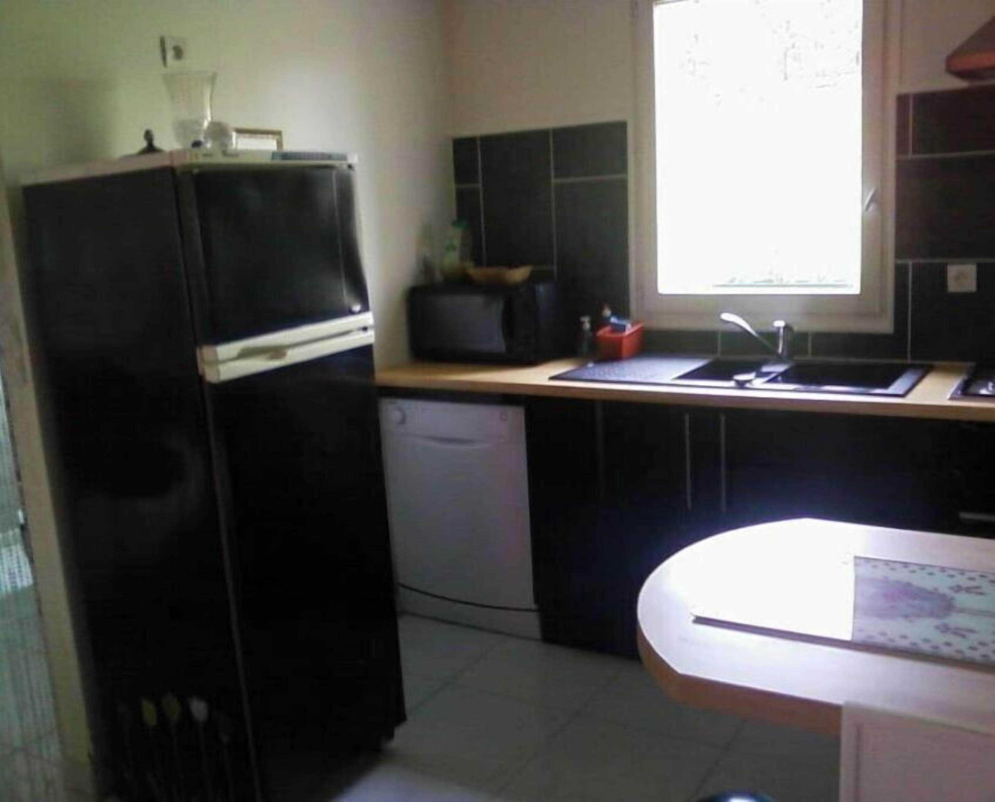 A compact kitchen with a refrigerator, a microwave, a sink, and a window.