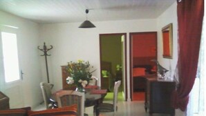 Un salon avec des coussins à rayures, une table à manger avec des chaises, un vase de fleurs et une lampe.