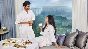 Una pareja en una habitación con un amplio ventanal con vistas a un paisaje urbano.