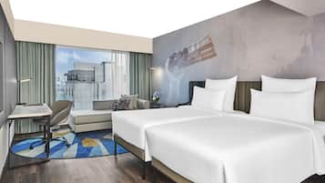 A modern hotel room with two beds, a desk, a chair, and a large window offering a city view.