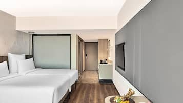 Habitación de hotel con una cama grande, televisión, kitchenette pequeña y comedor con una bandeja de frutas.