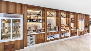 Zona de servicio de alimentos con vitrinas refrigeradas, estanterías de madera y una encimera de mármol.