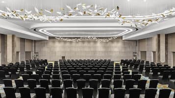 A conference room with rows of chairs, a podium, and a ceiling with hanging decorative elements.