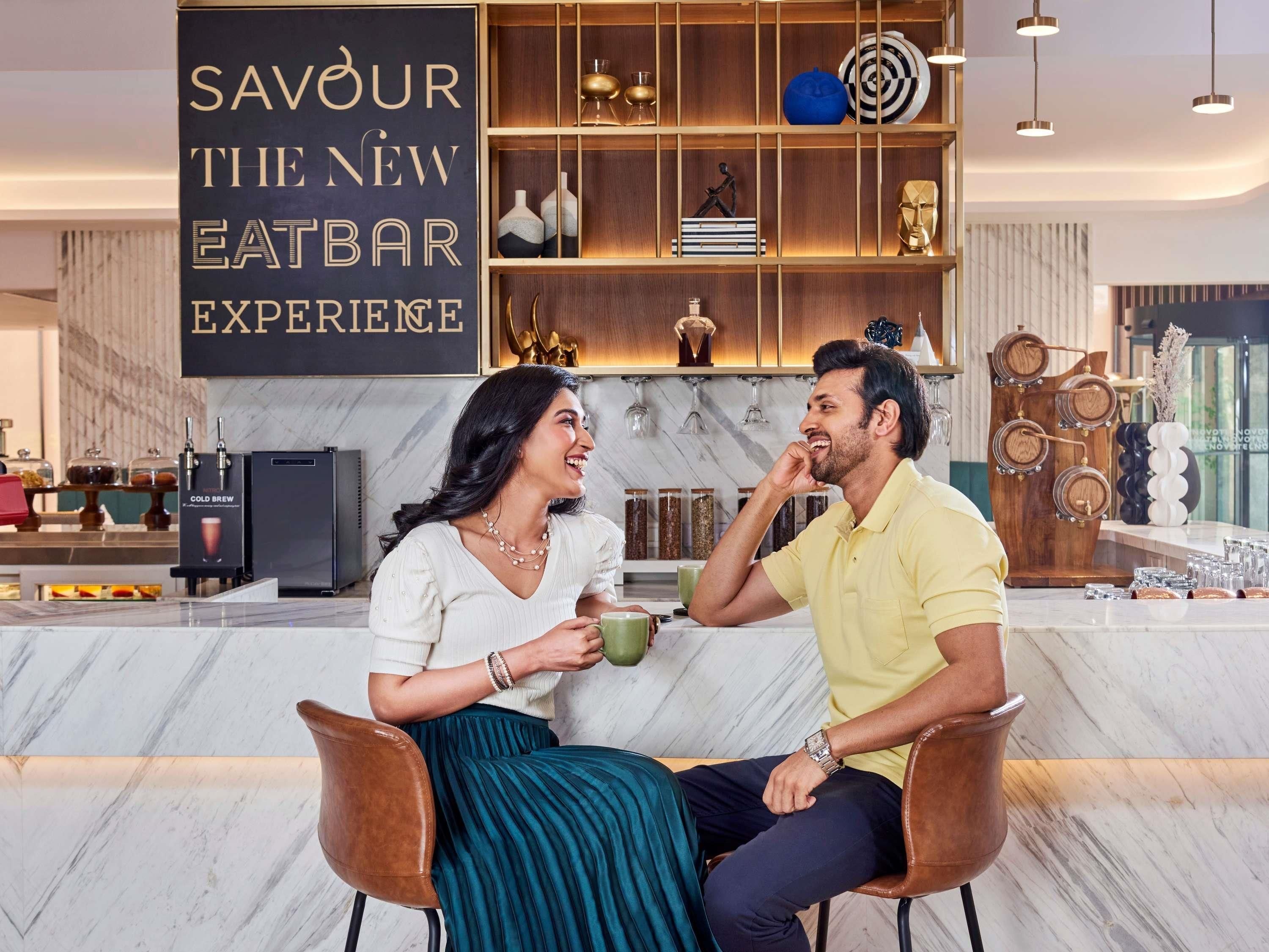 A modern eatery with a sign reading 'SAVOUR THE NEW EATBAR EXPERIENCE.'
