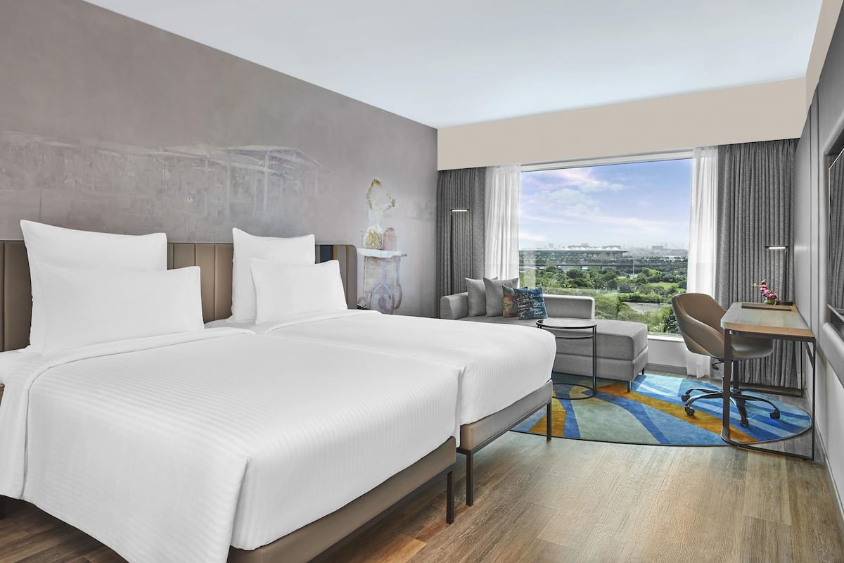 A modern hotel room with a large bed, a desk, and a view of the city.