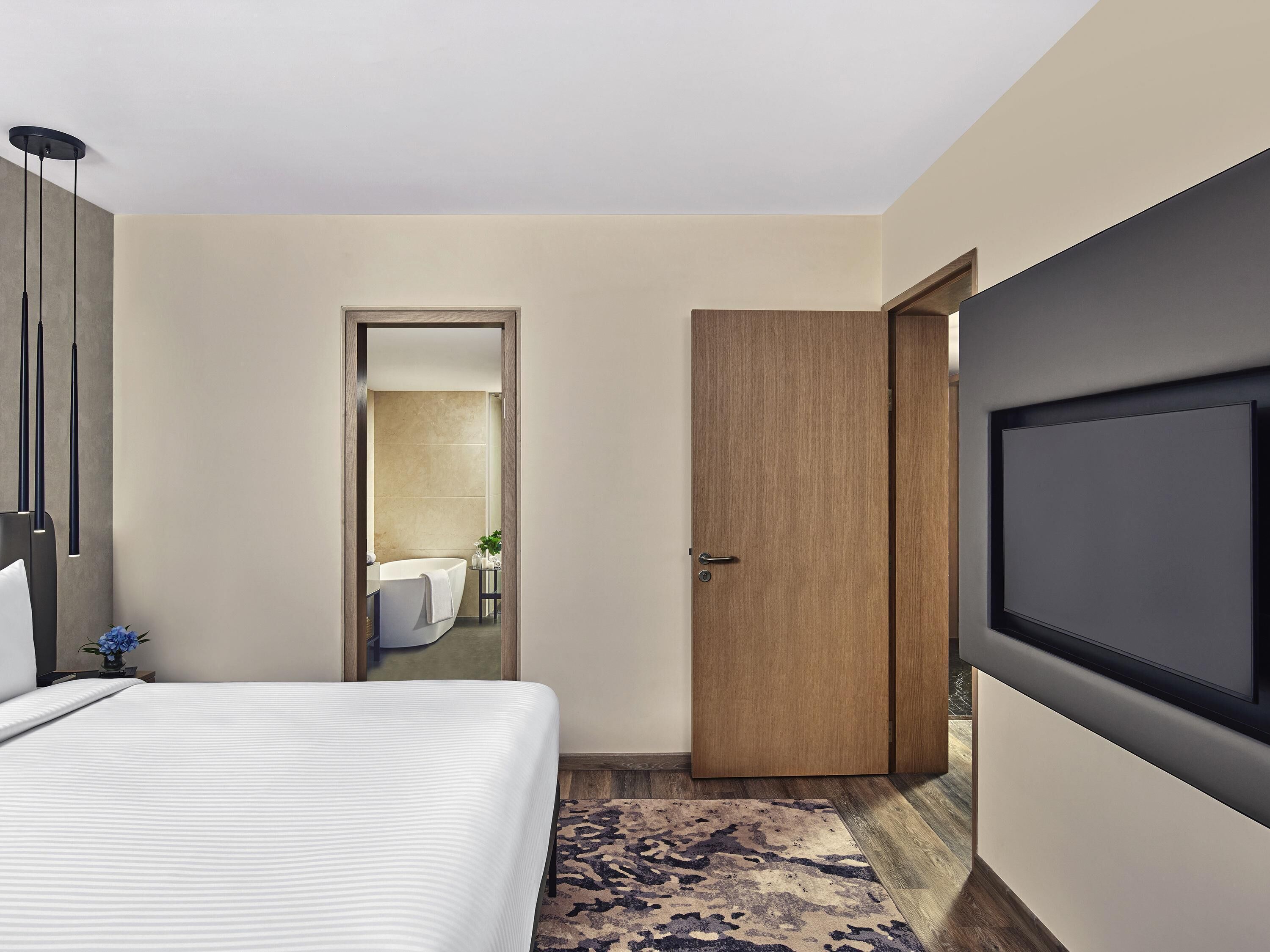 Ein Hotelzimmer mit Bett, Fernseher, Tür und einem durchgegangene Tür erkennbaren Badezimmer.