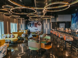 Un espace bar moderne avec des luminaires circulaires, une fresque murale et un comptoir.