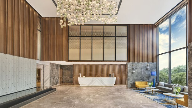 A spacious lobby with a reception desk, seating area, and large windows offering a view of the outdoors. - Novotel Mumbai International Airport (Mumbai)