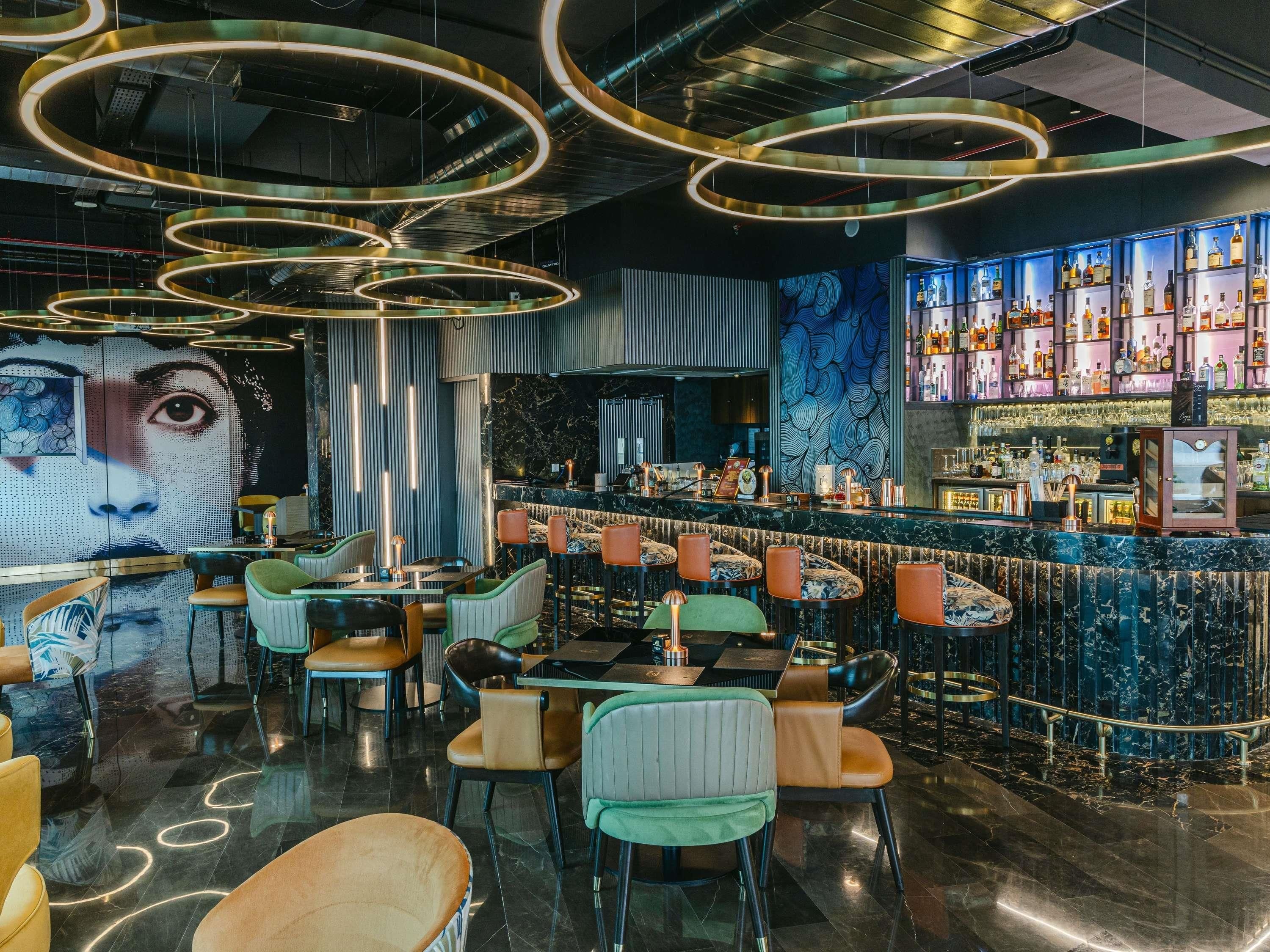 Zona de bar con mostrador de mármol, diversas opciones de asientos y un mural grande en la pared.