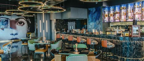 Eine Bar mit einer Marmor-Theke, verschiedenen Sitzmöglichkeiten und einem großen Wandgemälde.