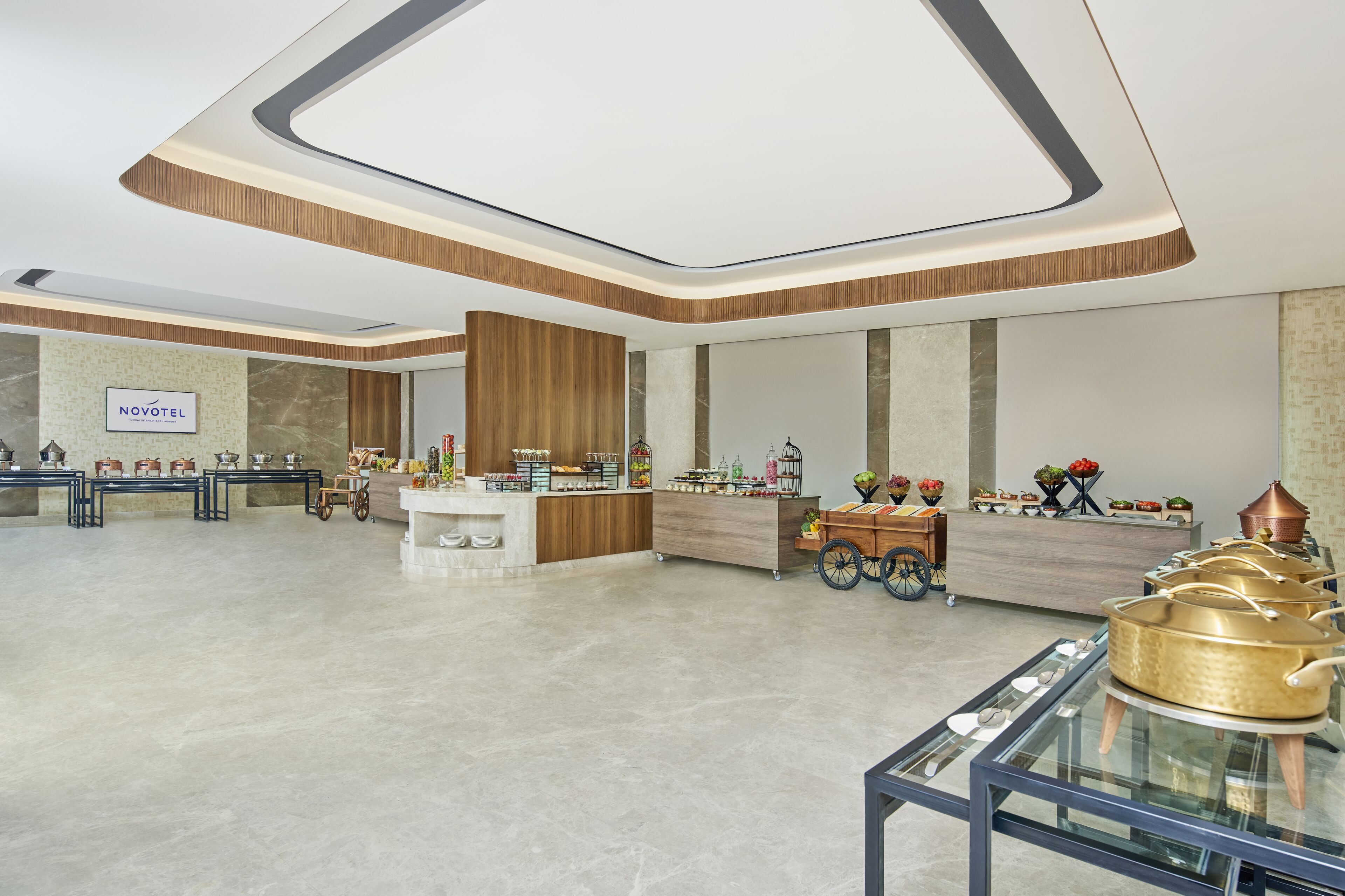 A spacious hotel lobby with a reception desk, a display of trophies, and a buffet setup.