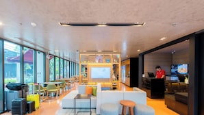 Eine moderne Hotelhalle mit Sitzgelegenheit, einer Rezeption und einem großen Fernseher.