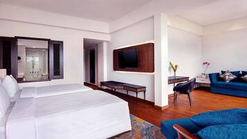 A modern hotel room with a large bed, a desk, a TV, and a sofa.