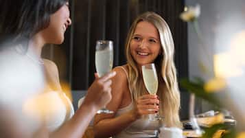 Dos personas sentadas a una mesa con una copa de champán, sugiriendo un evento social o celebratorio.
