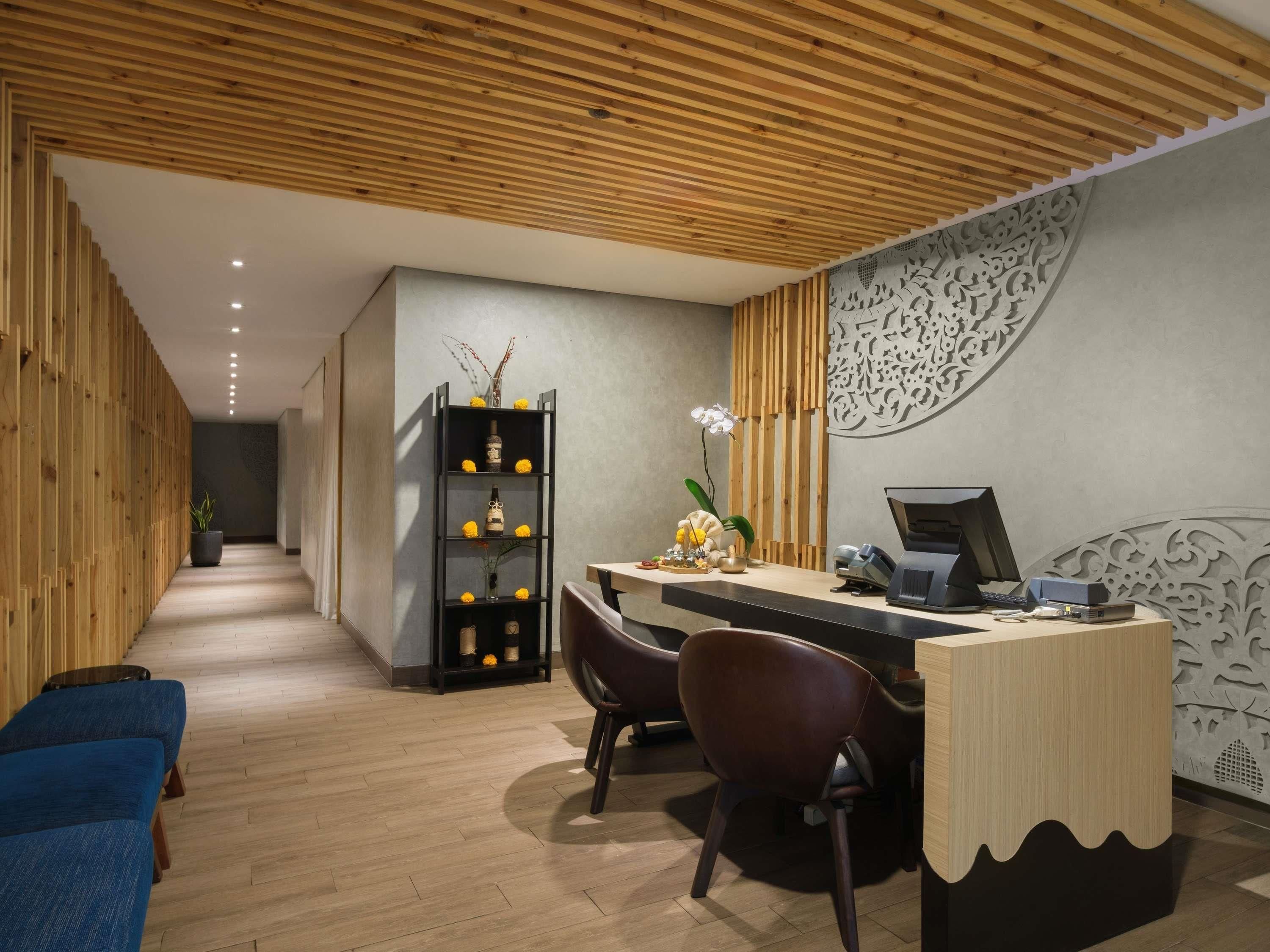 A reception desk with a computer, a chair, and a plant.