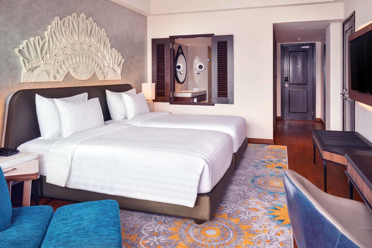 A hotel room with a large bed, a TV, a desk, and a seating area.