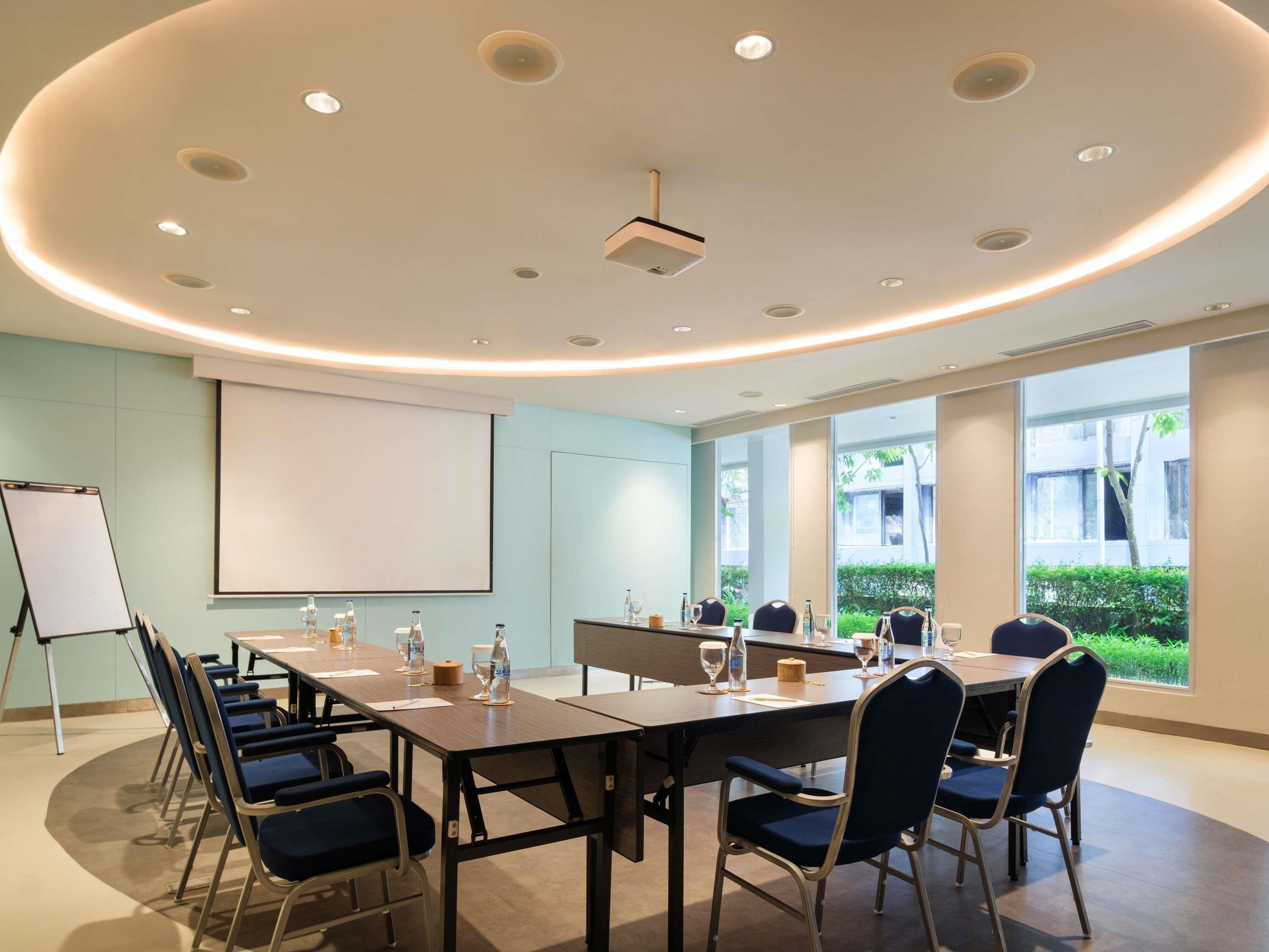 Una sala conferenze con un grande tavolo, sedie, un proiettore e una lavagna.