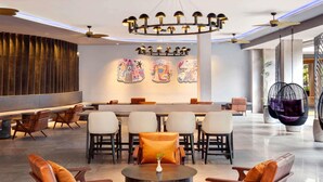 A modern lobby with a bar area, seating arrangements, and decorative wall art. - Grand Mercure Bali Seminyak (Seminyak)