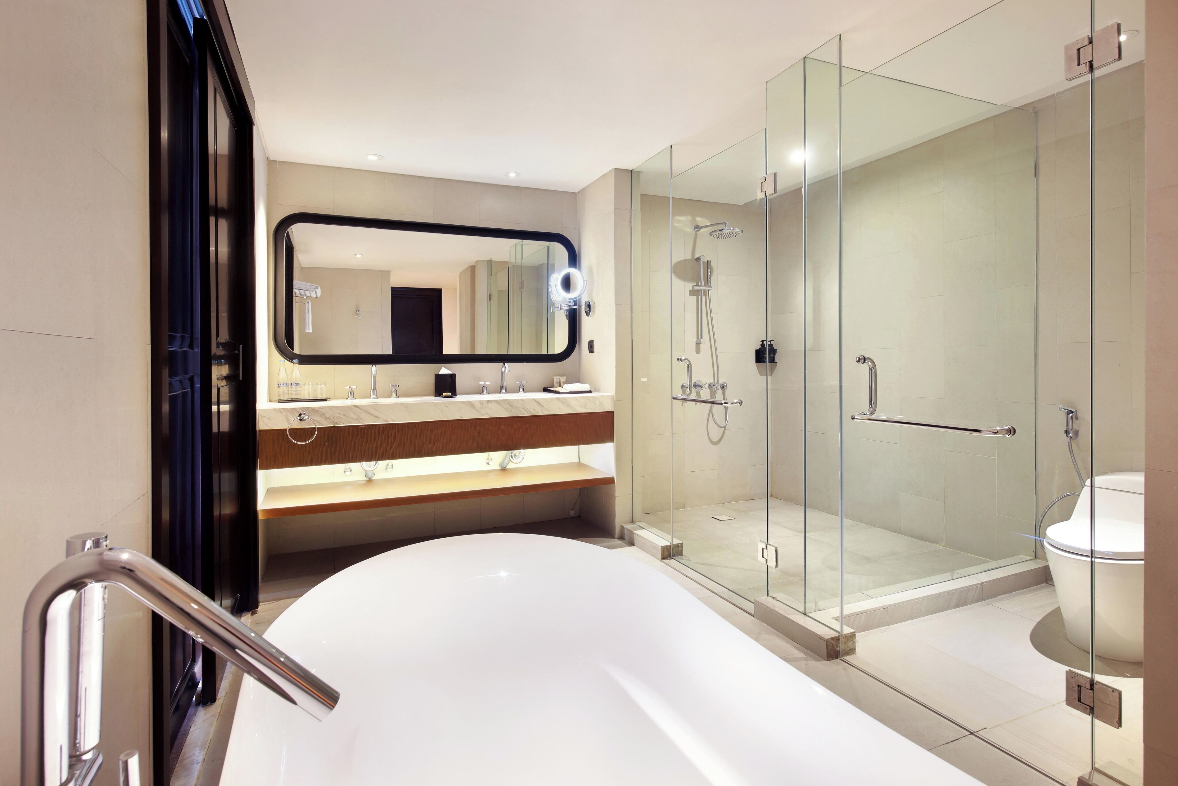 A modern bathroom with a large bathtub, a glass-enclosed shower, and a vanity with a mirror.