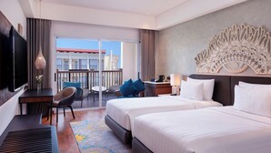 A hotel room with two beds, a desk with a TV, a balcony with a view, and a decorative wall piece.