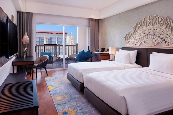 A hotel room with two beds, a desk with a TV, a balcony with a view, and a decorative wall piece. - Grand Mercure Bali Seminyak (Seminyak)