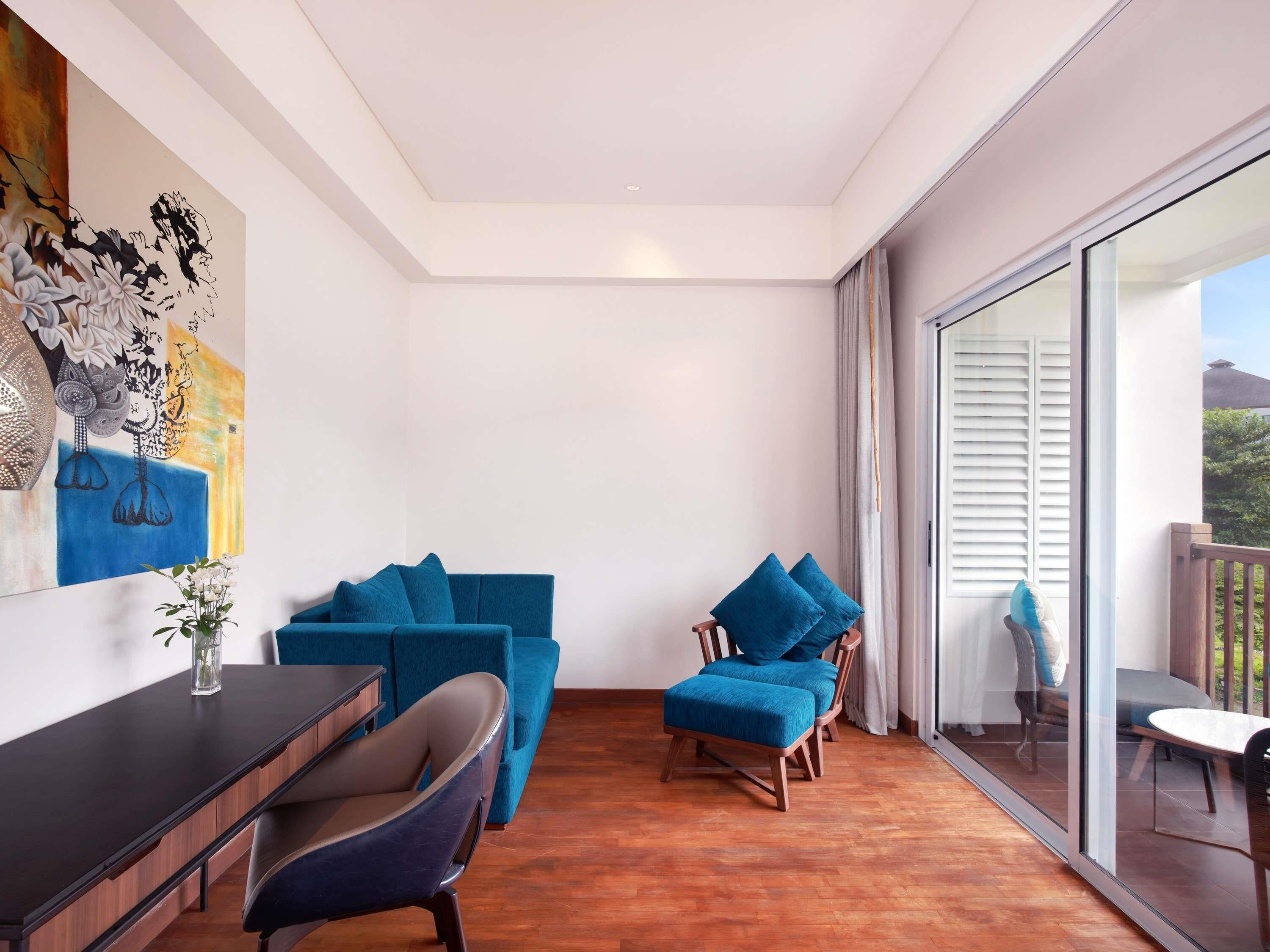 A modern living room with a blue sofa, a wooden chair, and a dining table.