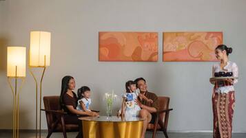 A room with a round gold table, two floor lamps, and a wall with two paintings.