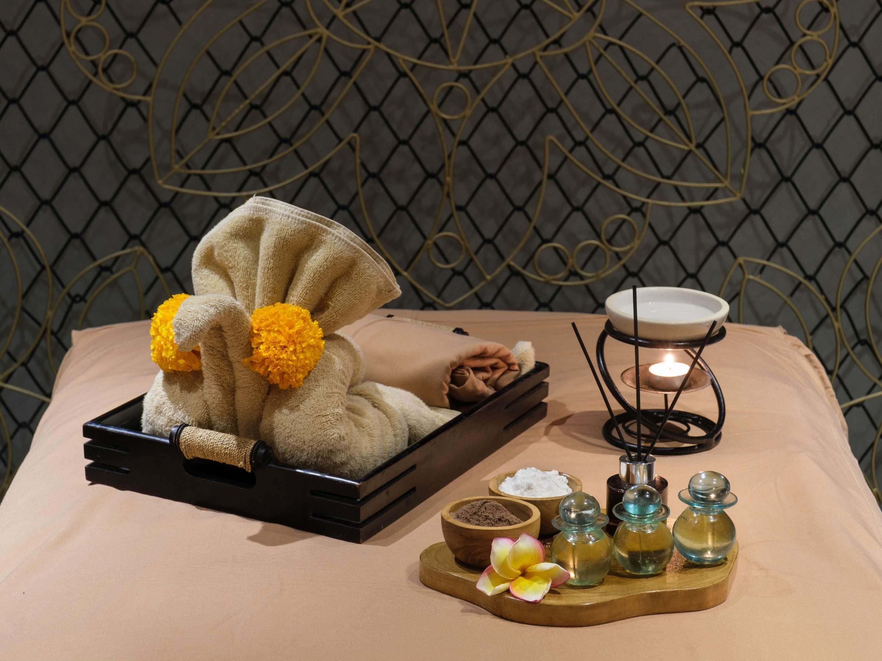 A neatly arranged spa setup with a towel, a candle, and various toiletries on a wooden tray.