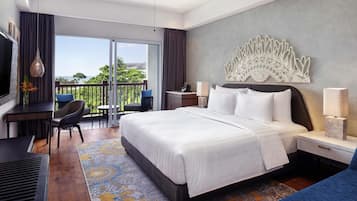 A hotel room with a large bed, a desk, a chair, a TV, a balcony with a view, and a decorative wall piece.
