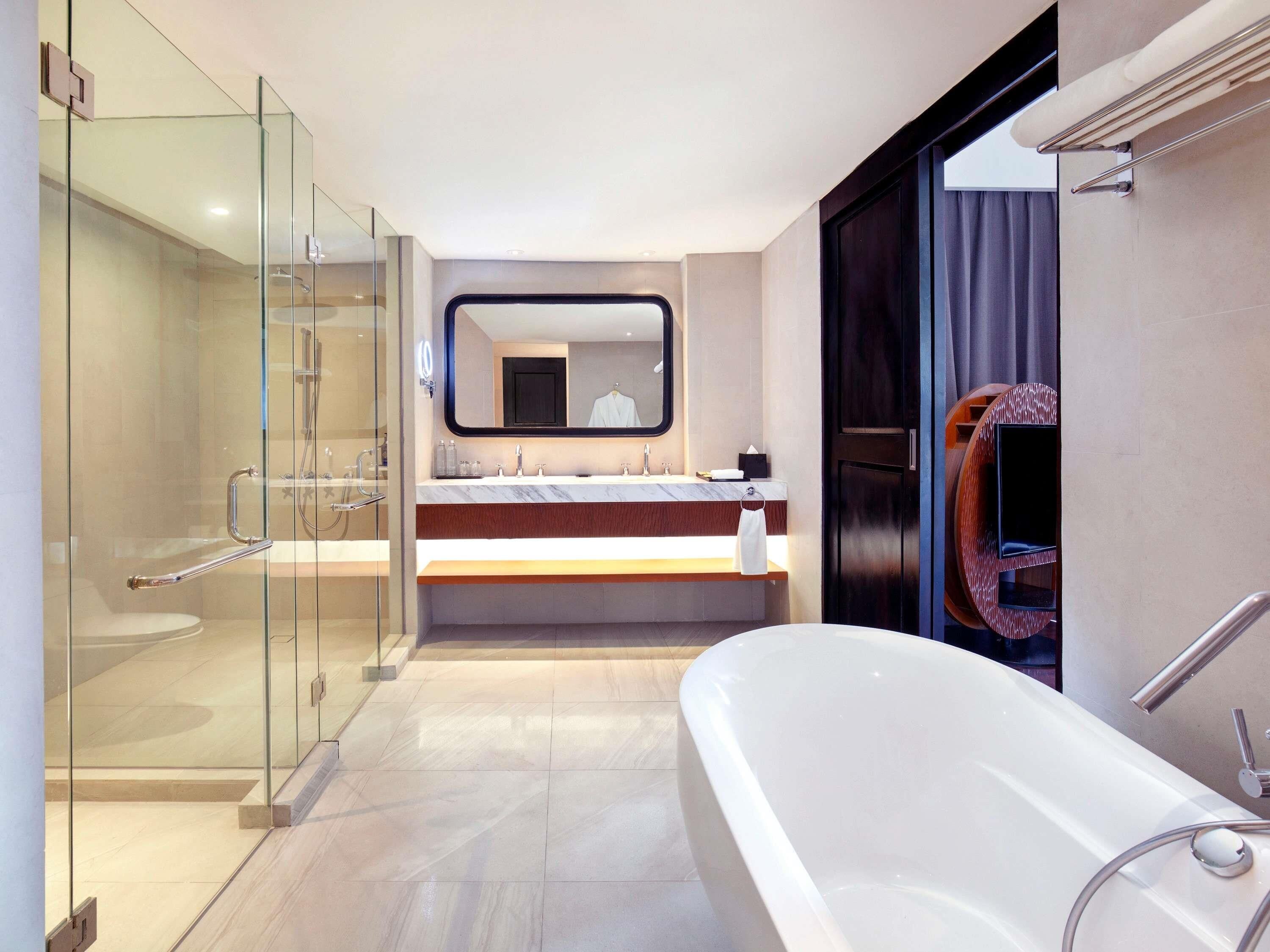 A modern bathroom with a glass-enclosed shower, a freestanding bathtub, and a vanity with a large mirror.