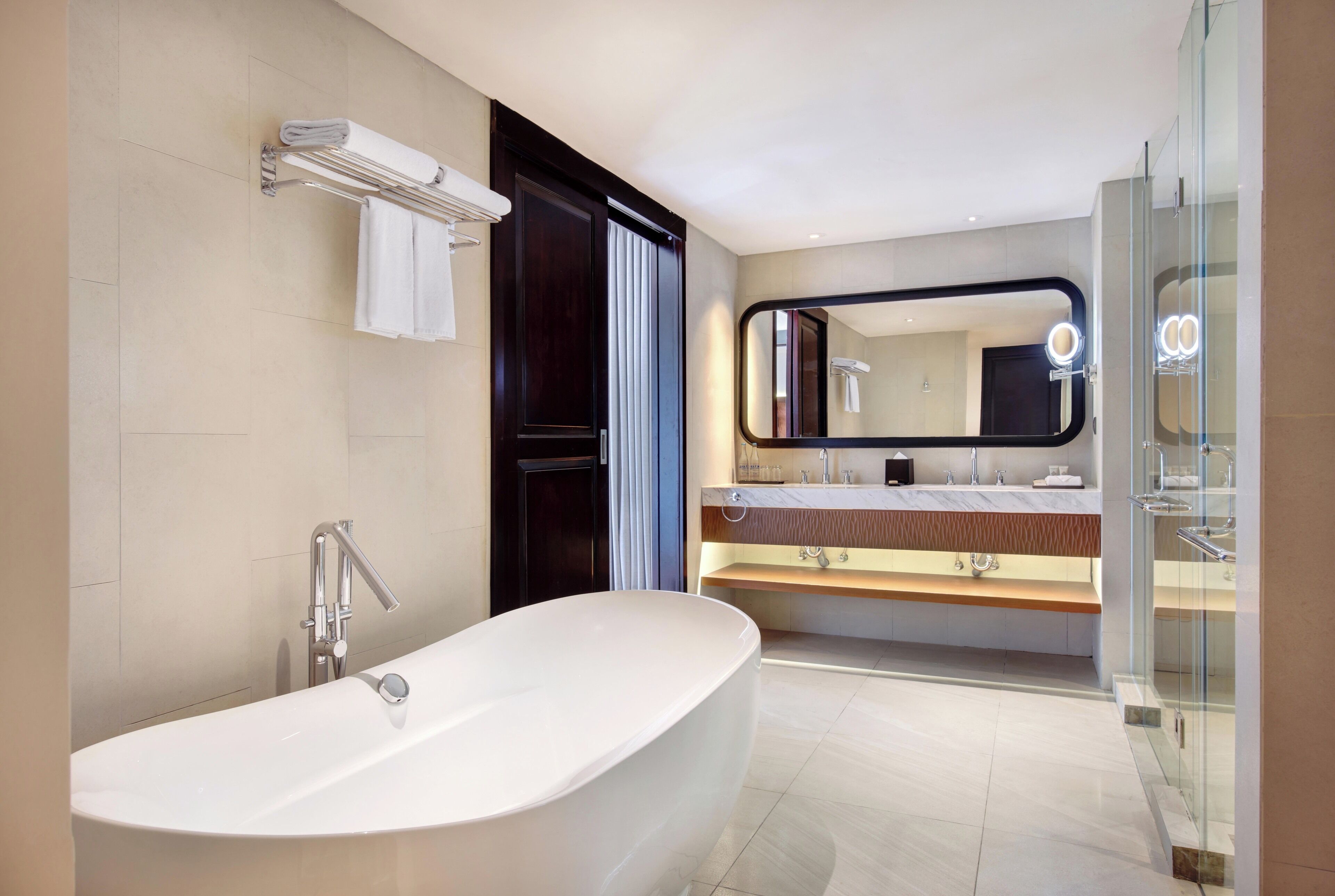 A modern bathroom with a freestanding bathtub, a vanity with a mirror, and a glass shower enclosure.