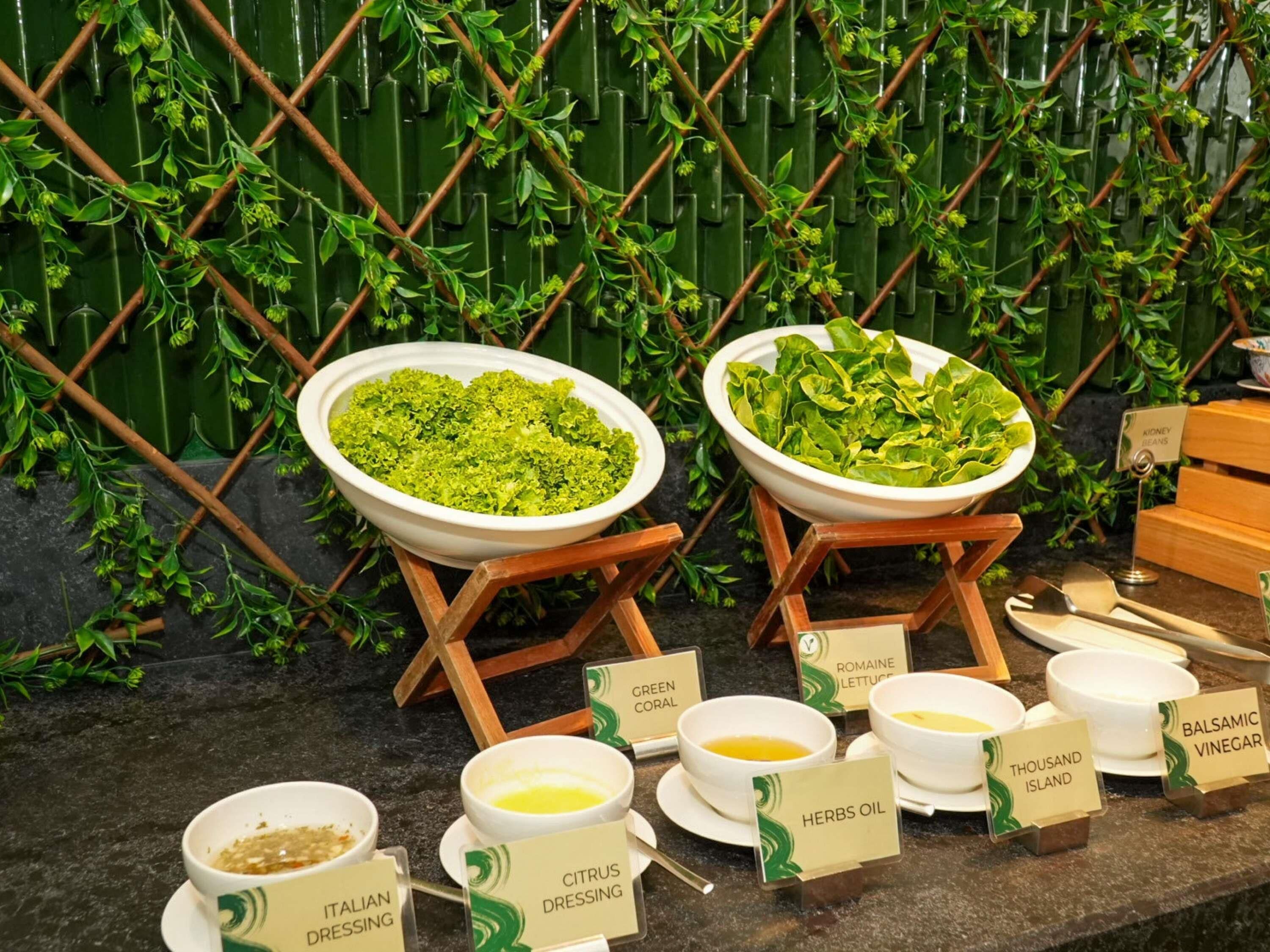 A salad bar with various greens and dressings, including Italian dressing and citrus dressing.
