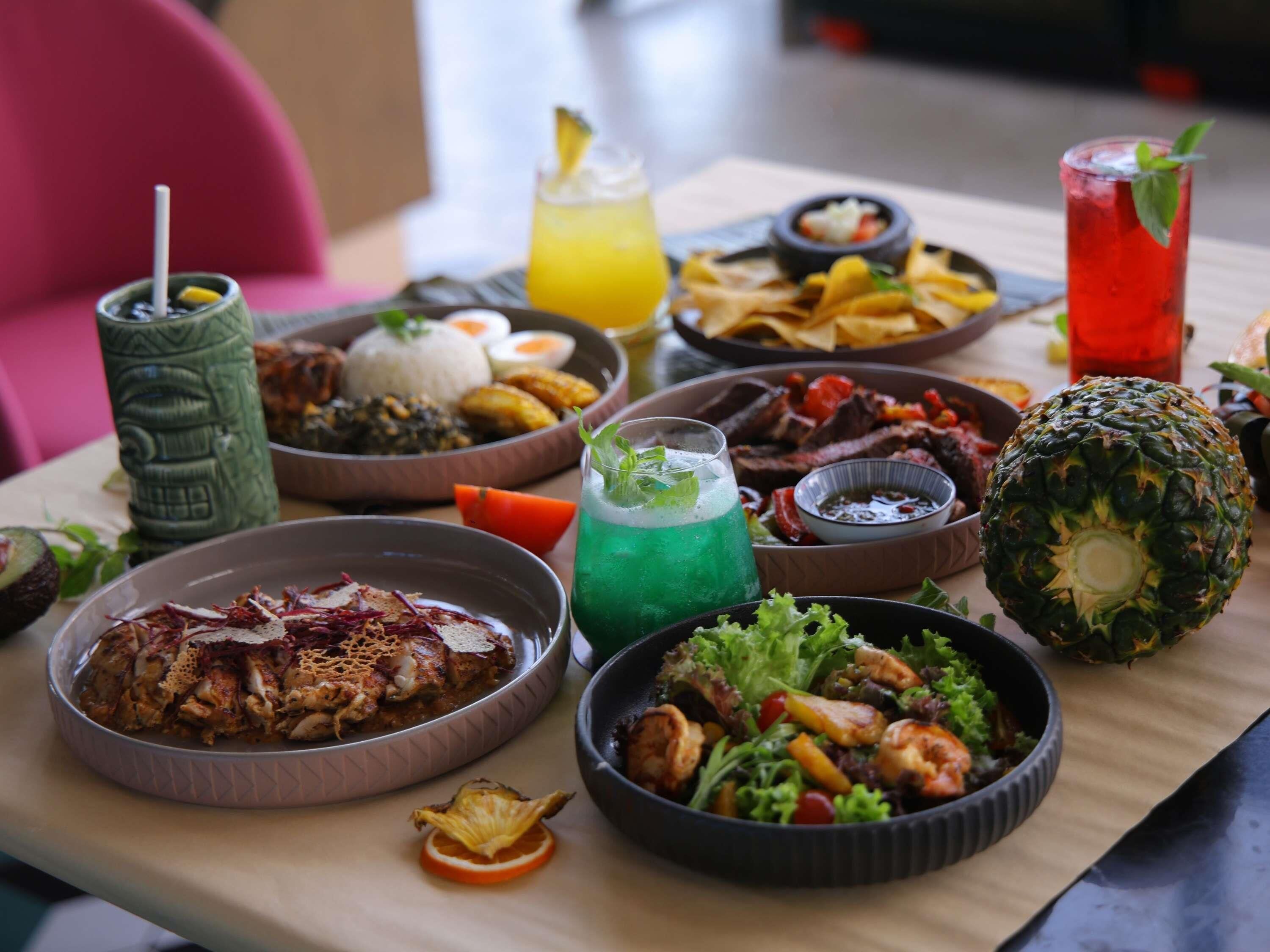 A table with various dishes, drinks, and a decorative pineapple centerpiece.
