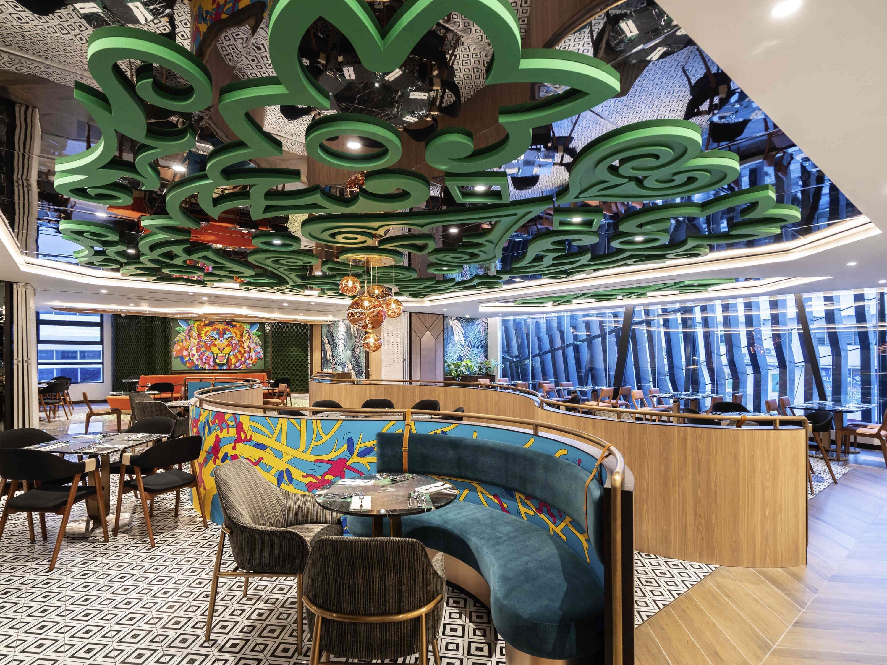 Un interior moderno con una zona de estar curva, un suelo estampado y un techo con diseños abstractos en verde.