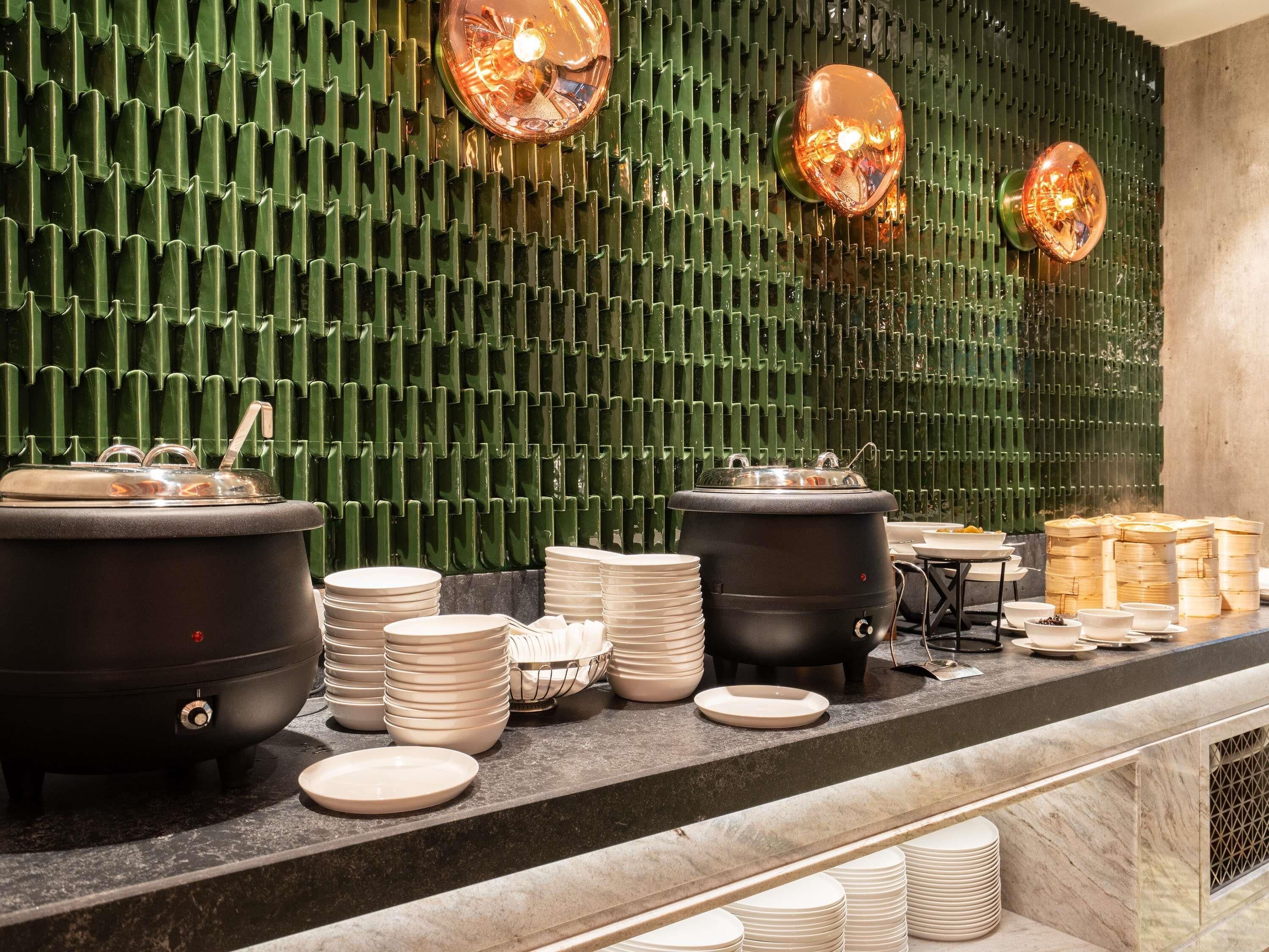 A buffet setup with multiple serving stations, including hot food and beverage dispensers, and a variety of plates and bowls.